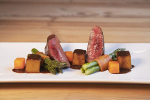 Gourmetgericht mit Rindersteak und Gemüsebeilage auf weißem Teller angeordnet, künstlerische Präsentation