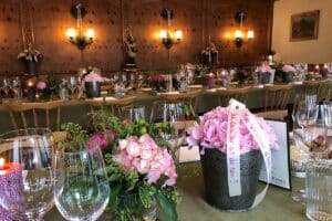 Festlich dekorierte Tische mit Blumenarrangements in einem Bankettsaal für eine Veranstaltung.