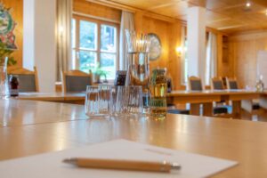 Konferenzraum mit einem Holztable, Gläsern und einer Karaffe für Wasser sowie Getränkeflaschen