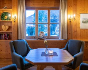 Behaglicher Innenraum mit Holzdekoration, Tisch mit Vase und Kerze, Ausblick nach draußen.